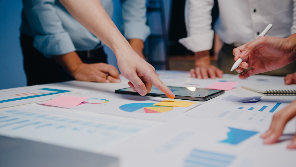 People pointing to diagrams laid out on a table
