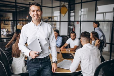 Programme manager standing in front of a desk of Project Managers