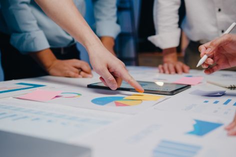 People pointing to diagrams laid out on a table